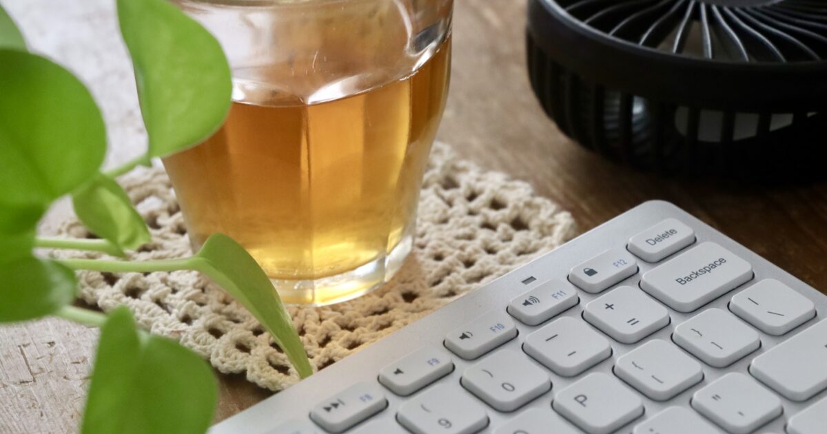 アイスティーとキーボードと卓上ファンと観葉植物のデスクトップ