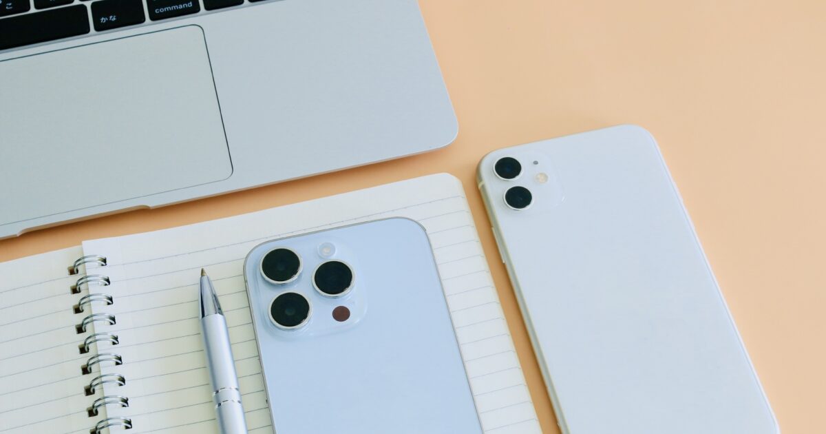 ノートパソコンと二台のスマートフォンとノートとボールペンのフラットレイ