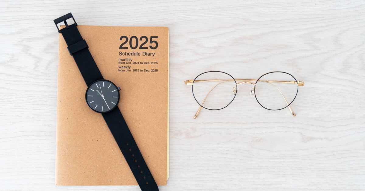 2025年スケジュール帳と腕時計と丸眼鏡のフラットレイ